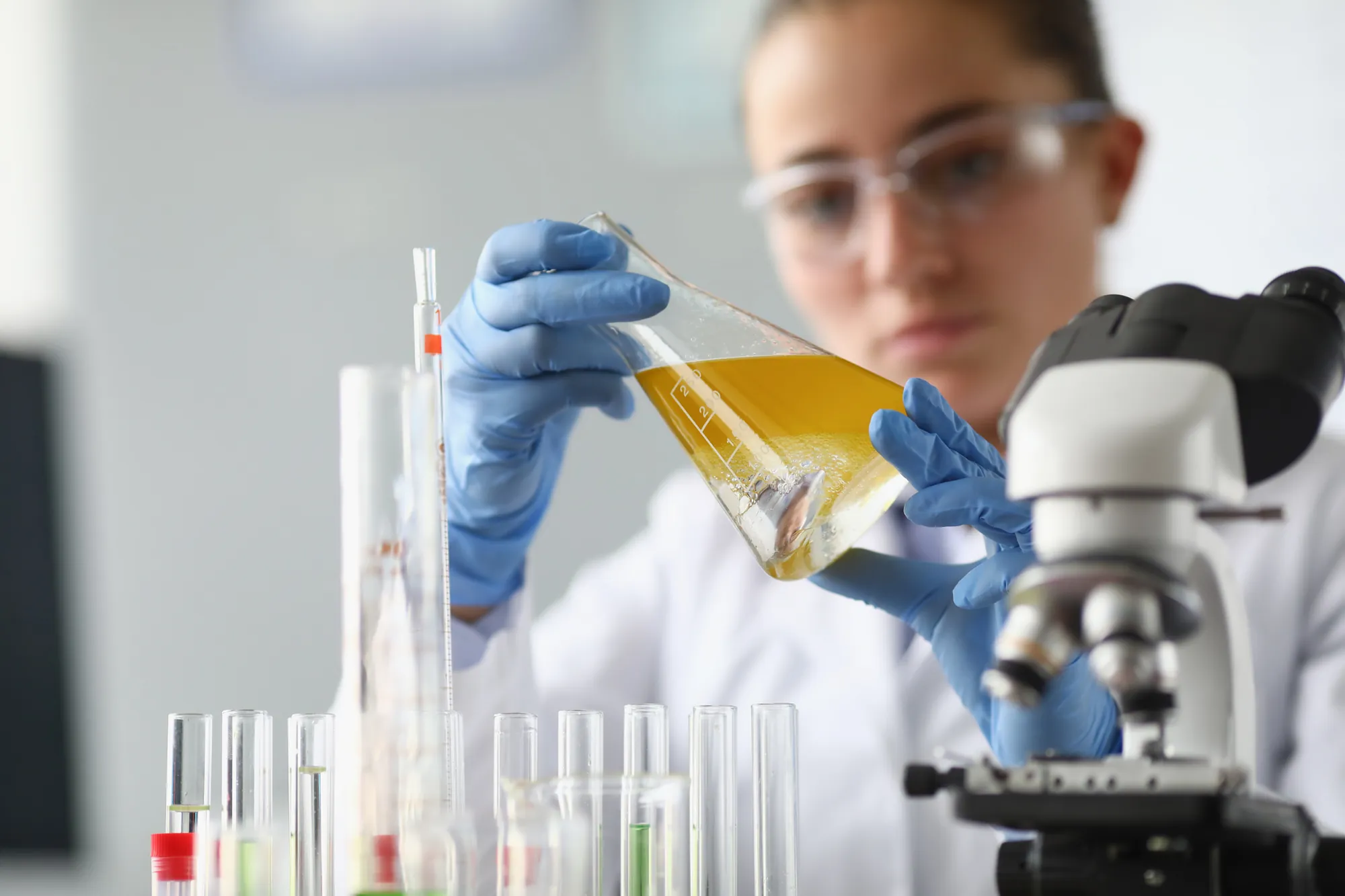 Scientist pouring a liquid sample beside a microscope