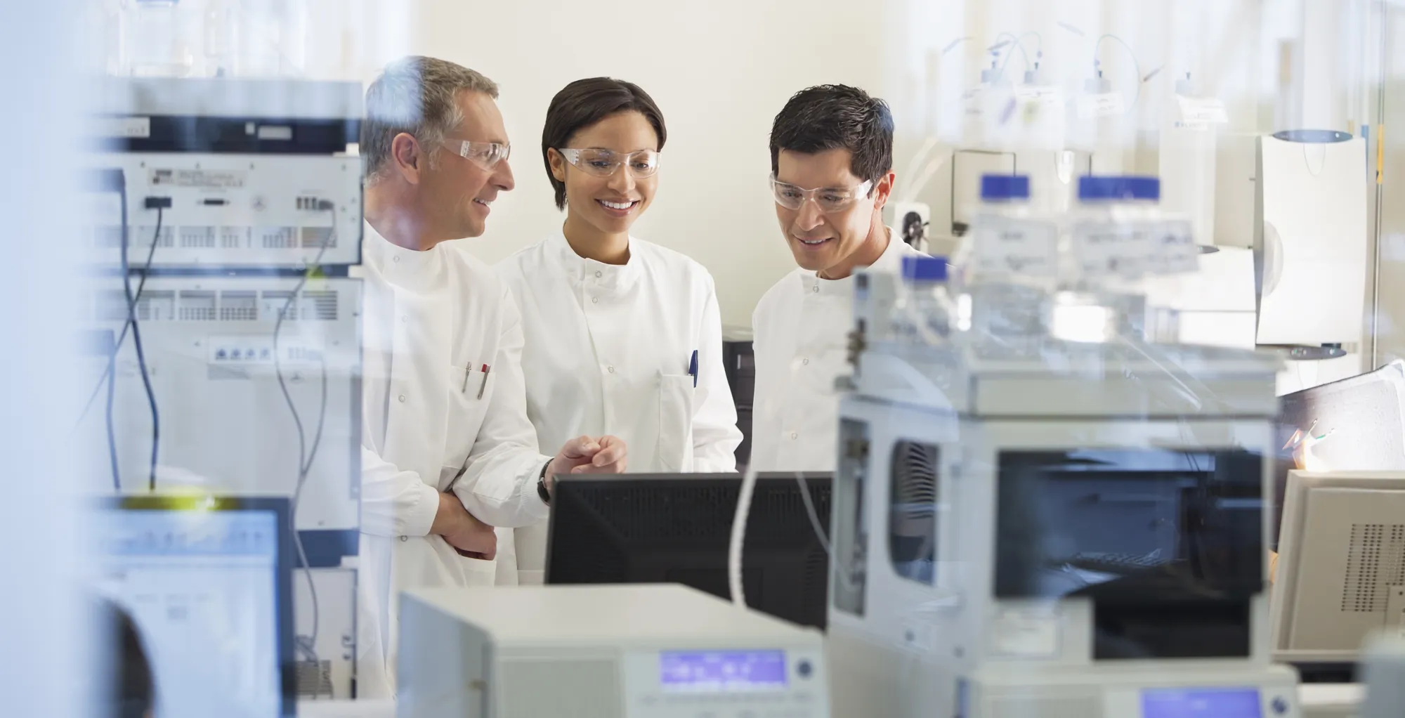 Three scientists reviewing chromatography results at an HPLC workstation
